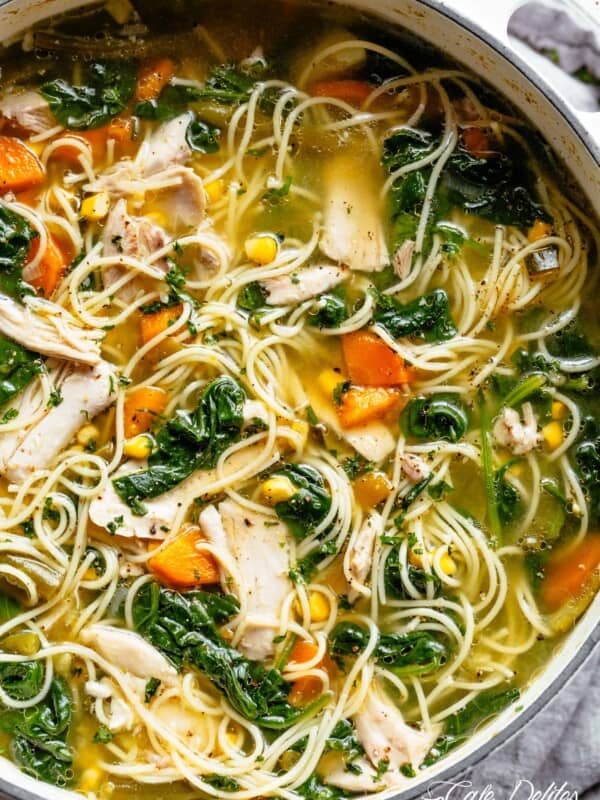 Homemade Chicken Noodle Soup loaded with carrots, spinach, corn and egg noodles mixed through a cloudy broth in a bowl.