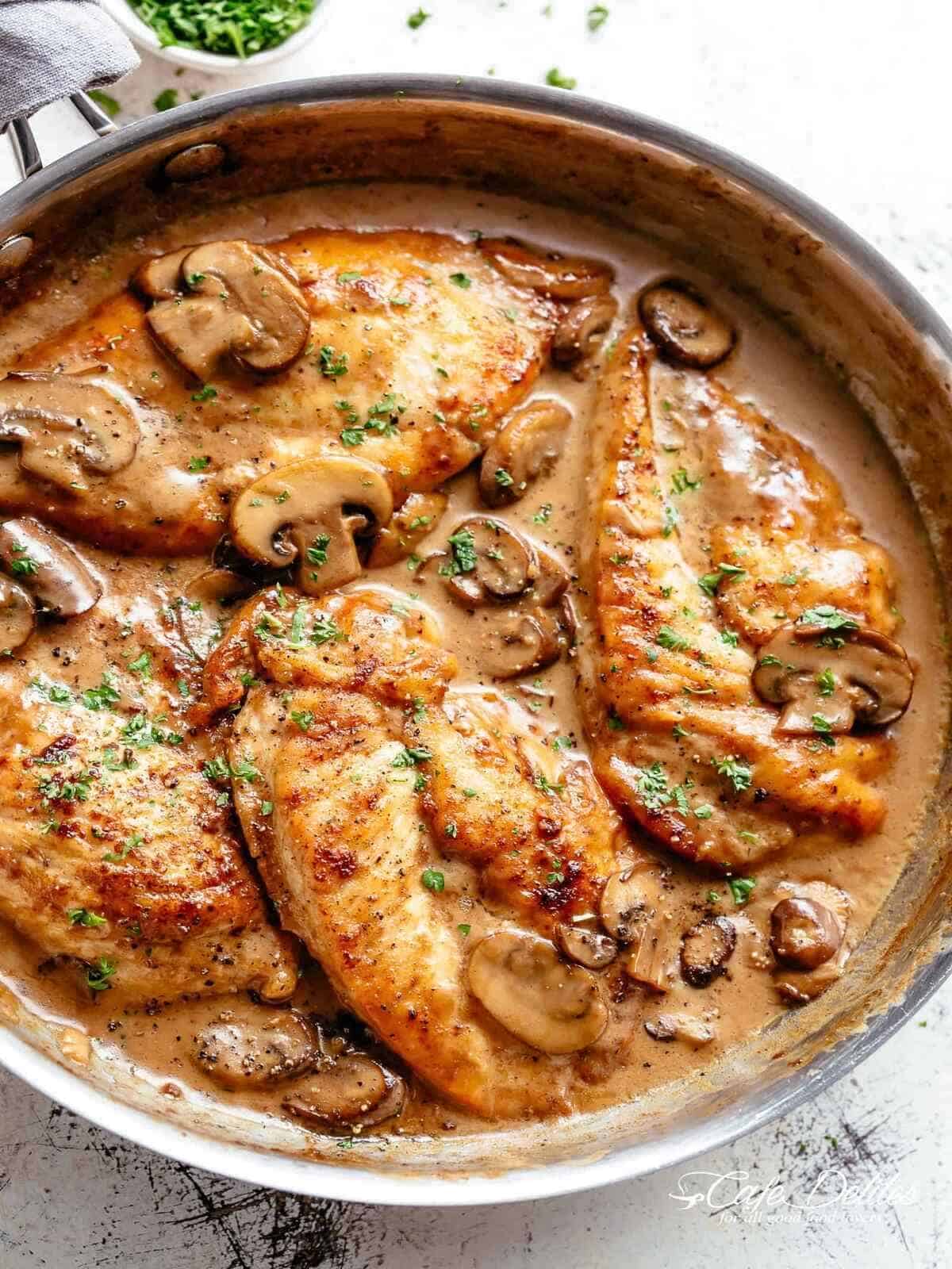 Easy Creamy Chicken Marsala | cafedelites.com Chicken breasts in a creamy, brown marsala sauce with mushrooms and fresh herbs in a pan.