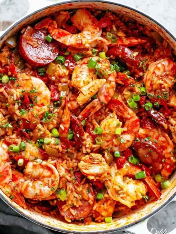 Close-up image of a colorful, freshly prepared jambalaya with shrimp and sausage, cooked in a white pot, ready to be served.
