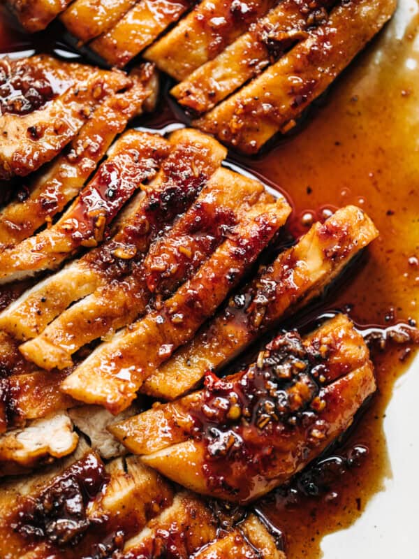 Chicken breast with hot honey butter sauce on a white plate.